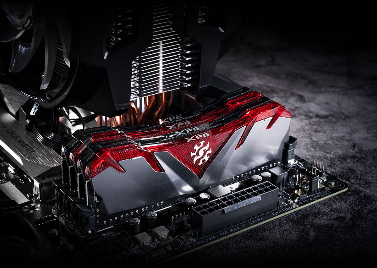 Quad GAMMIX D30 memory modules on a motherboard, with alternating translucent black and red top covers. Behind them is a large tower CPU cooler